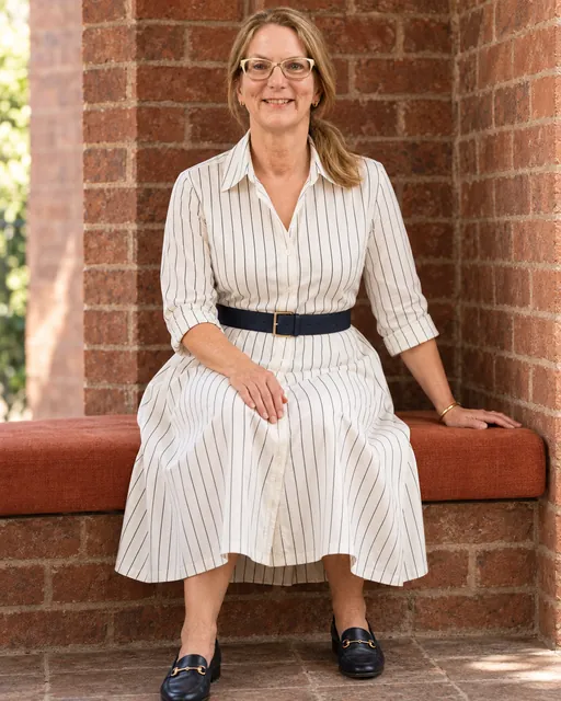 Anna Haranas seated in a striped shirt dress, showcasing expertise in quality assurance.